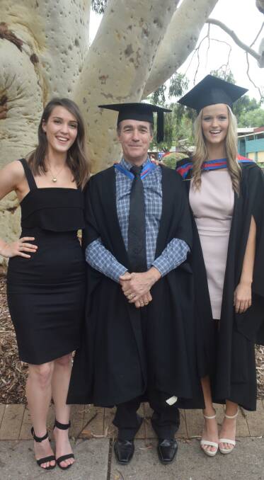 DOUBLE ACT: Twins Helena Bush (left) and Victoria Bush with their father Tony Bush are graduating in the same cohort, but couldn't be more different. Photo: Amelia Mills.