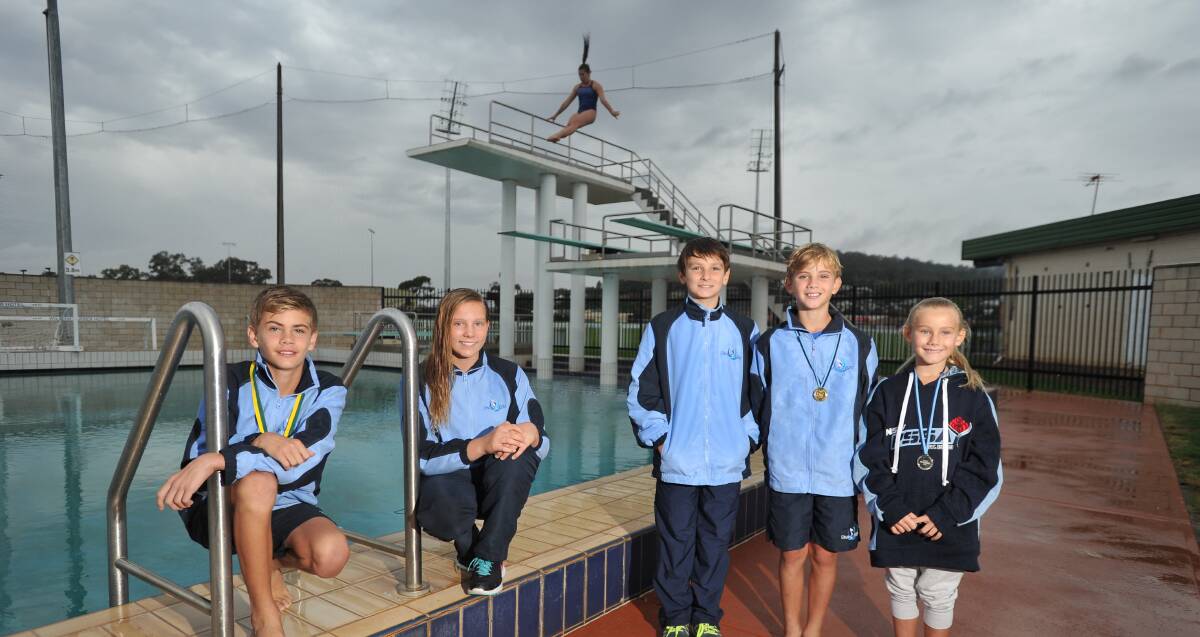 SWEET SUCCESS (from left): Angus Grigg, Grace Barrett, Samson Lucas, Edouard Grigg and Philomena Grigg show off their medals as Madeleine Lucas gets in some more practice on the diving board. Picture: Laura Hardwick
