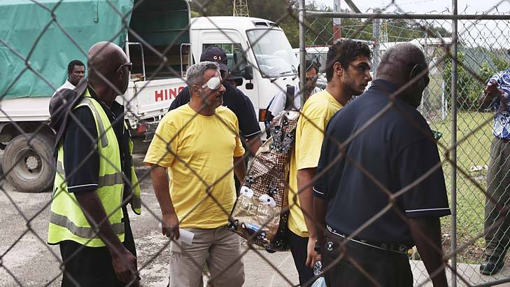 Tight security: Two asylum seekers, one with an injury, leave Manus Island airport on Thursday. Photo: Nick Moir