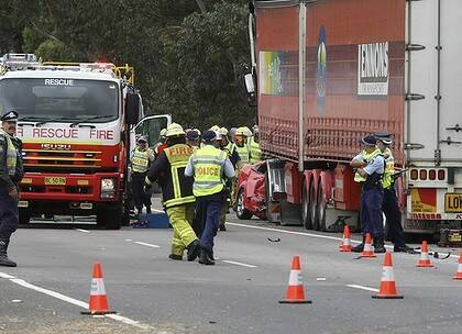 Loss … police and rescue staff investigate a crash on the Hume Highway, south of Sydney, after a semi-trailer collided with a red Ford, killing all three occupants.