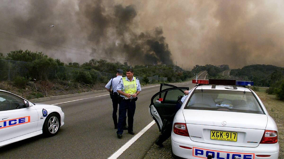 Police block the Princes Highway as a massive bushfire approaches the southern Sydney suburb of Heathcote on Boxing Day 2001. Photo: REUTERS