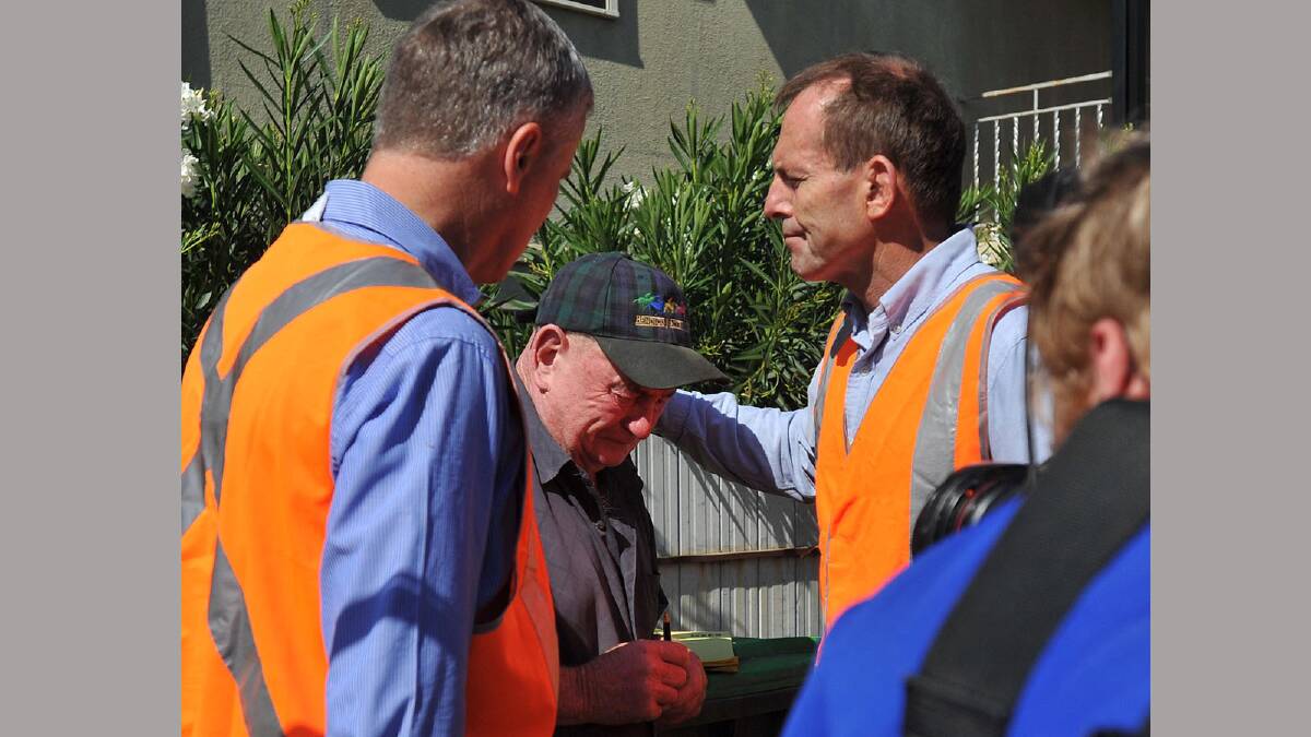 Michael McCormack and Tony Abbott comforts North Wagga resident Allan Bell as he cleans up his flood damaged home. Picture: Oscar Colman