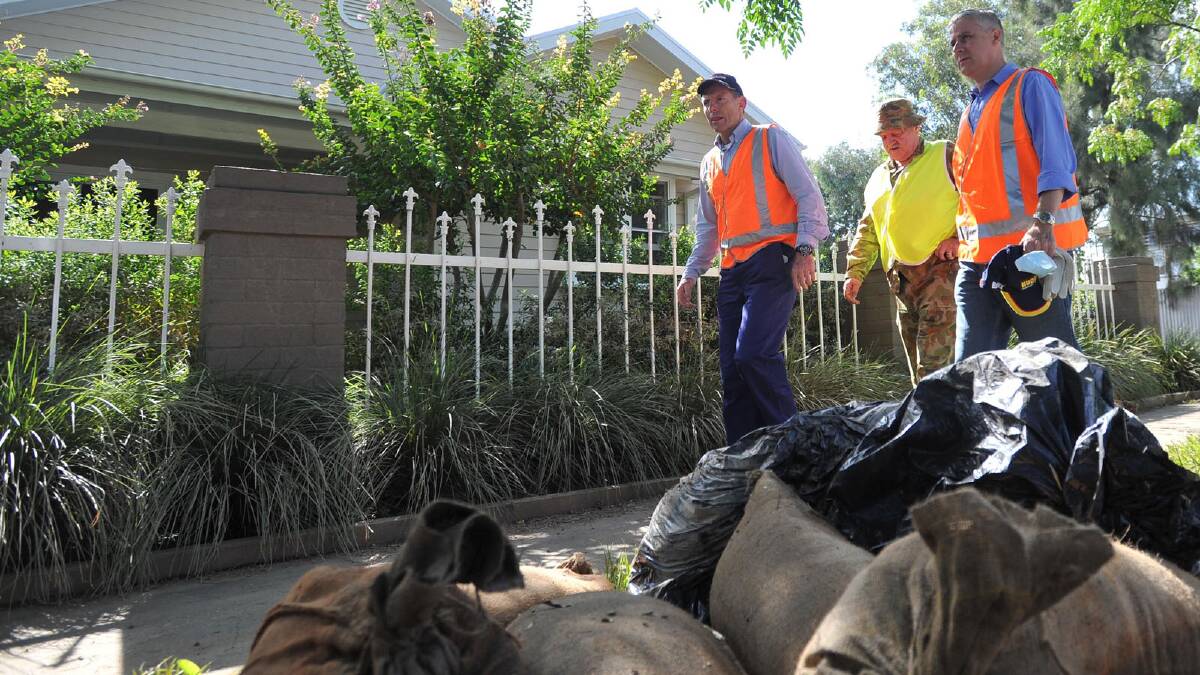 Tony Abbott surveys the discarded belongings of North Wagga homes which were affected by flood water. Picture: Oscar Colman