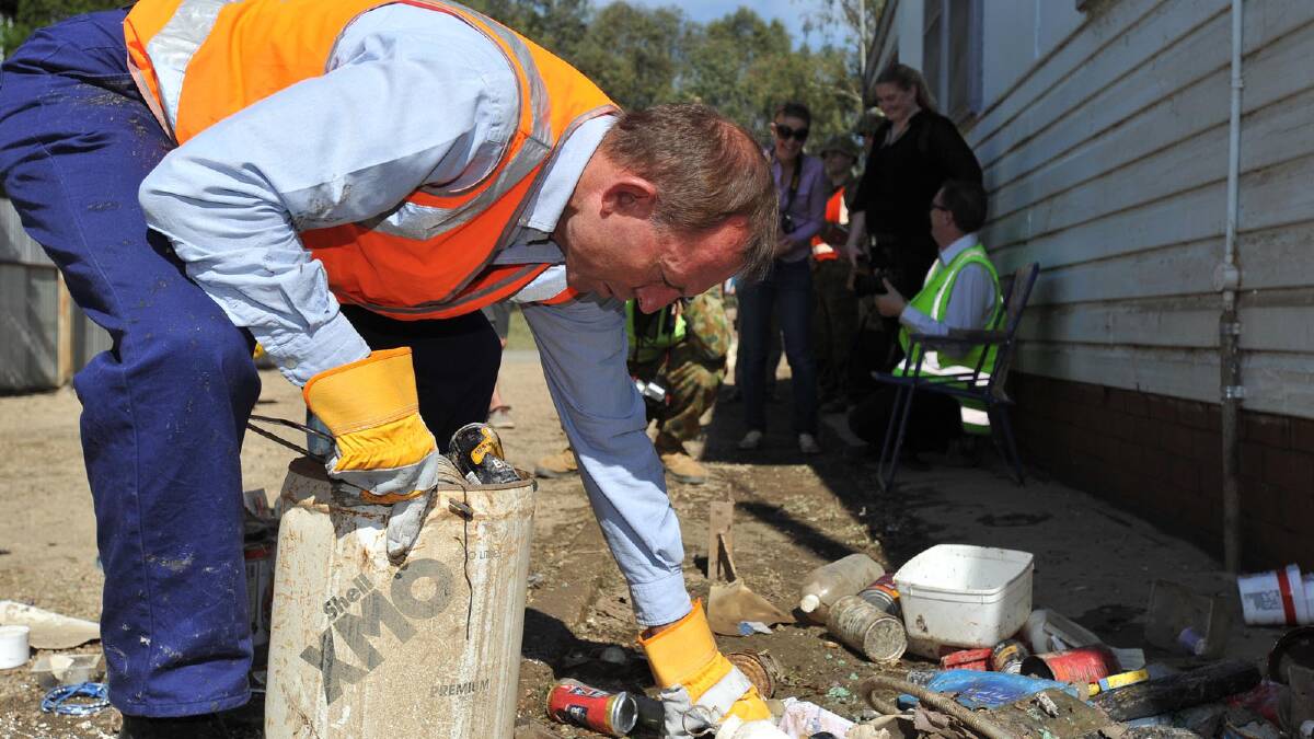 Tony Abbott cleans rubbish from North Wagga resident Allan Bell's home. Picture: Oscar Colman