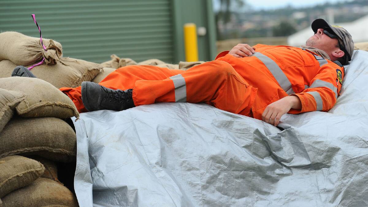 A weary SES volunteer takes a hard-earned nap during Prime Minister Julia Gillard's visit. Picture: Addison Hamilton