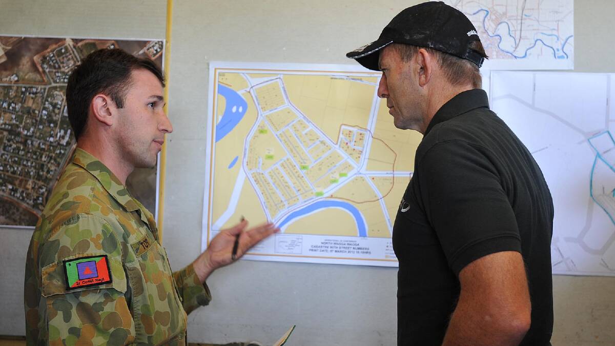 Tony Abbott is briefed before assisting North Wagga residents with the clean up. Picture: Oscar Colman