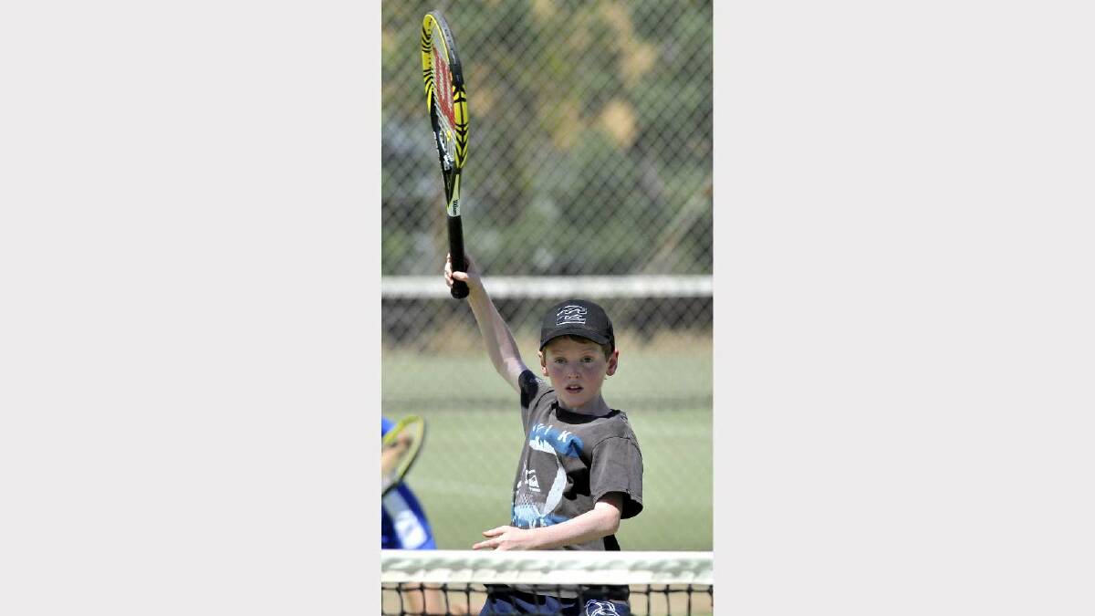 TENNIS: Junior tennis at Bolton Park. Rex Mather, 10, has his racquet high above the net. Picture: Les Smith