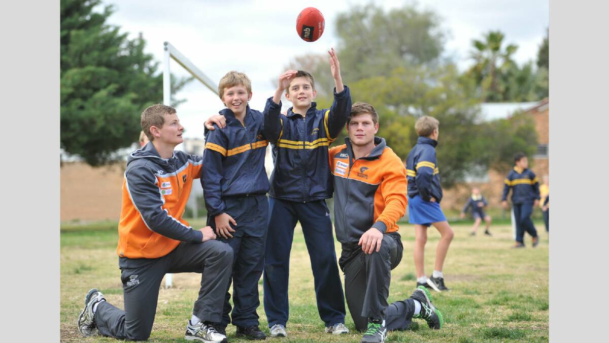 GWS players Sam Schulz and Taylor Adams with South Wagga Public School students Harry Reynolds and James Forwood, both 11, during a visit last year. Picture: Oscar Colman