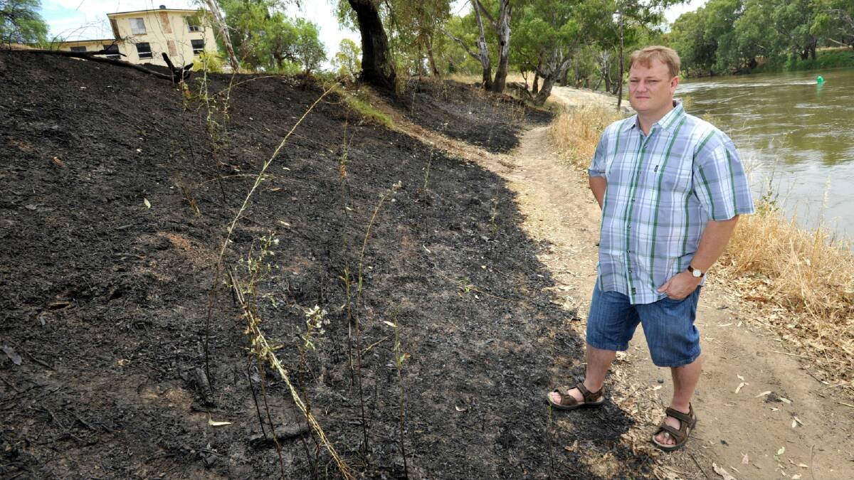 Fr Michael Armstrong of St John's Anglican Church checks burnt out scrub as a result of a deliberately lit fire near the St John's rectory. Picture: Les Smith