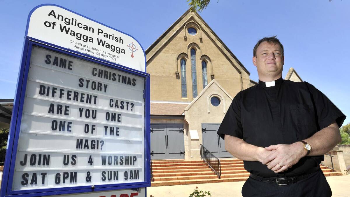 Reverend Michael Armstrong with the sign at the front of Wagga's Anglican Church. Picture: Les Smith