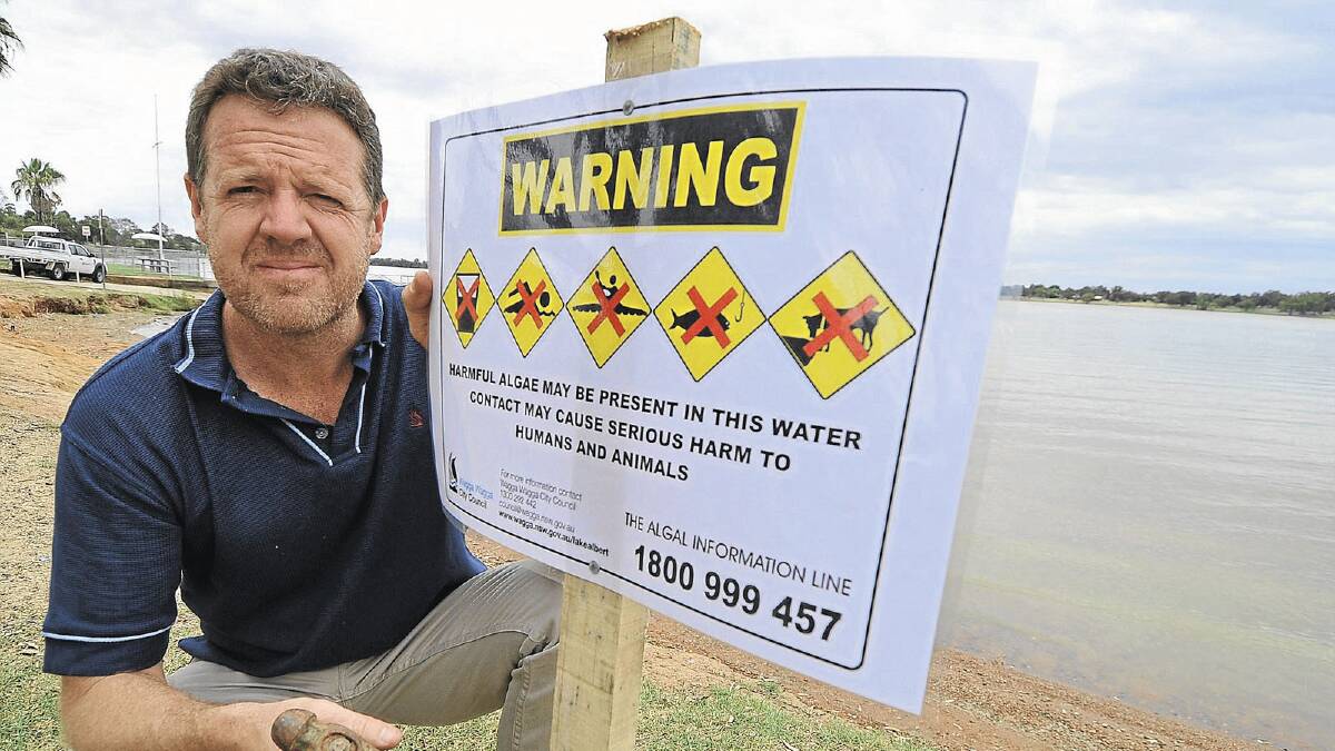 Wagga City Council’s environmental monitor officer Jason Carroll places warning signs around Lake Albert after its waters were declared unsafe following high levels of blue-green algae. Picture: Addison Hamilton