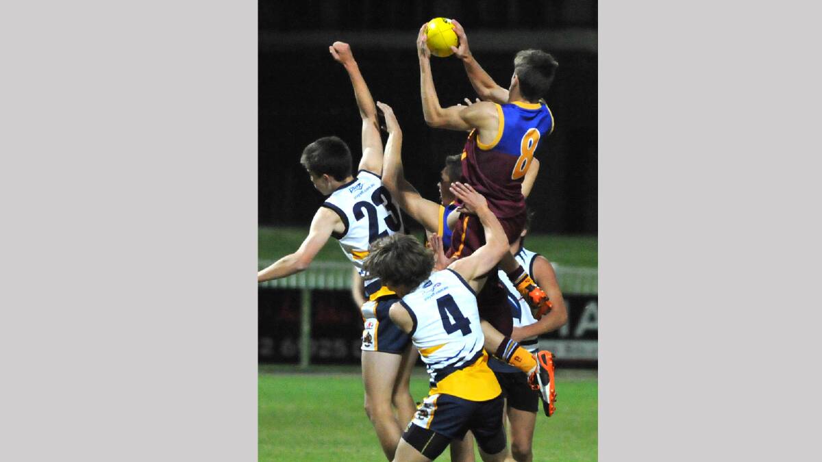 Mater Dei's Jock Cornell takes a flying mark over Kooringal players Fraser Noack and John Broughton. Picture: Les Smith