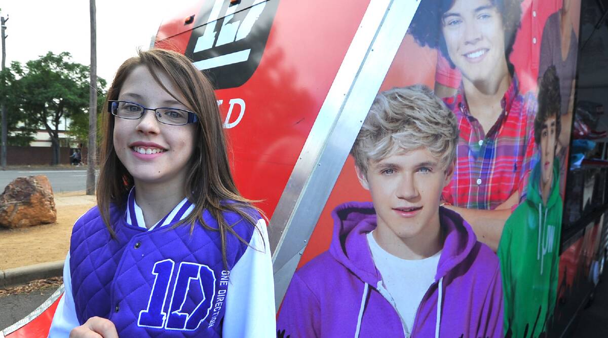 Danielle Wheeler, 12, in her new One Direction jacket poses next to an image on Niall Horan after the official merchandise truck visited the city today. Picture: Addison Hamilton
