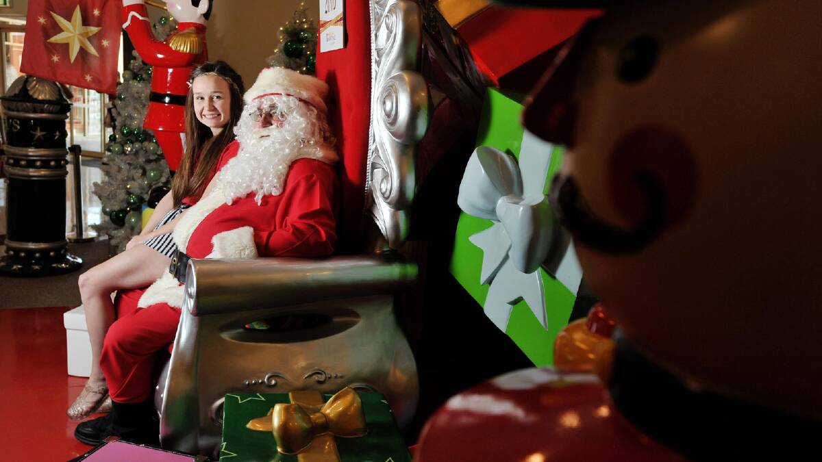 Santa's little helper Jasmine Dunn sits with Santa at the marketplace. Picture: Alastair Brook
