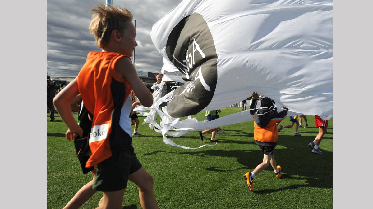 Wagga Auskick players run through a Wagga Wagga banner at the opening of the redeveloped Robertson Oval. Picture: Les Smith