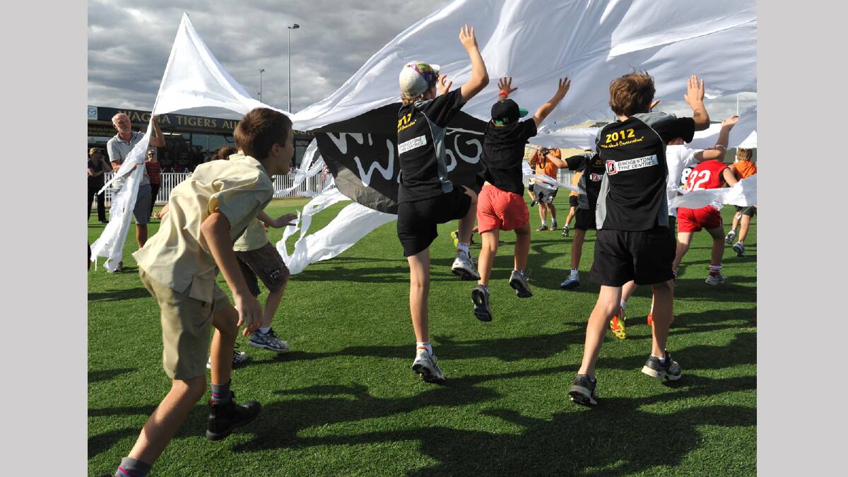 Wagga Auskick players run through a Wagga Wagga banner at the opening of the redeveloped Robertson Oval. Picture: Les Smith