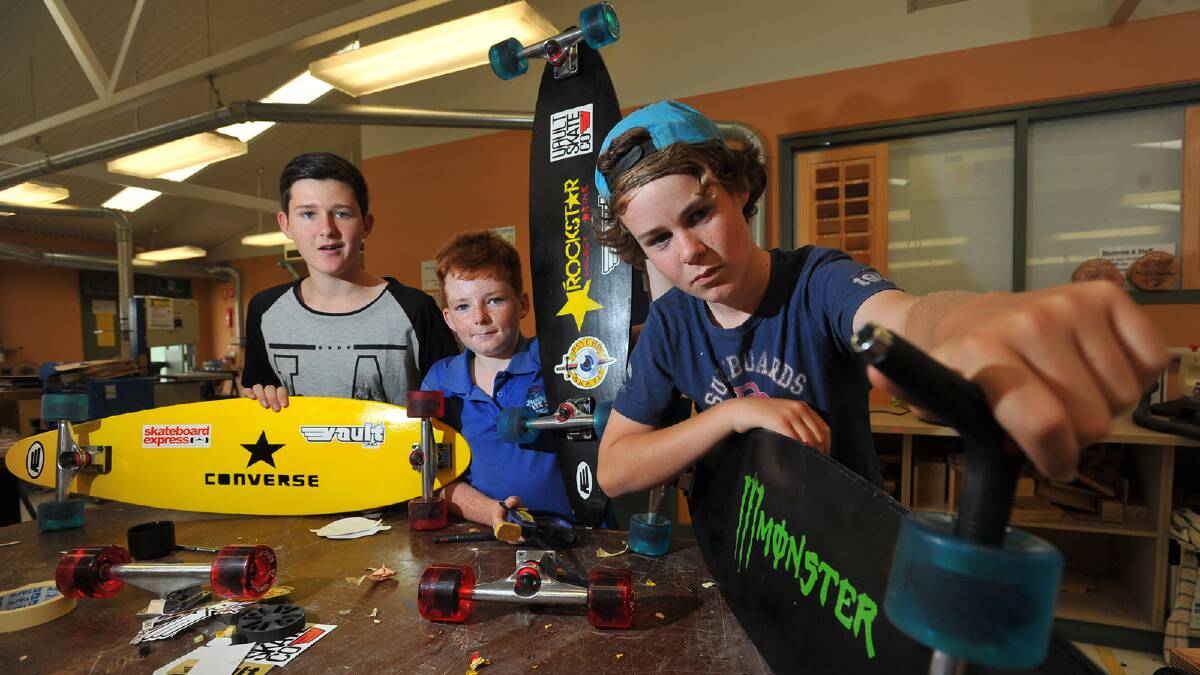 Cody Bramich, Brody Guthrie and Angus Allan apply the finishing touches to their longboards. Picture: Addison Hamilton