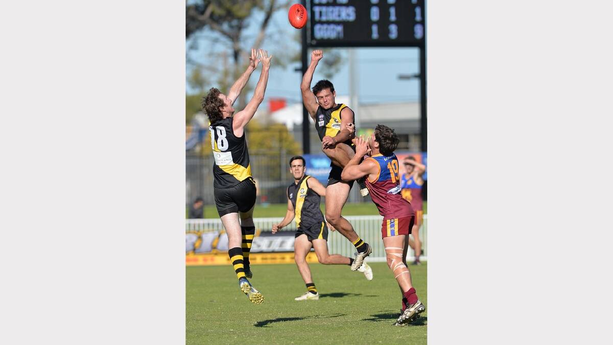 Tigers Matt Noonan and Lahn Shephard jump high in a contest with GGGM's Daniel Steele. Picture: Michael Frogley