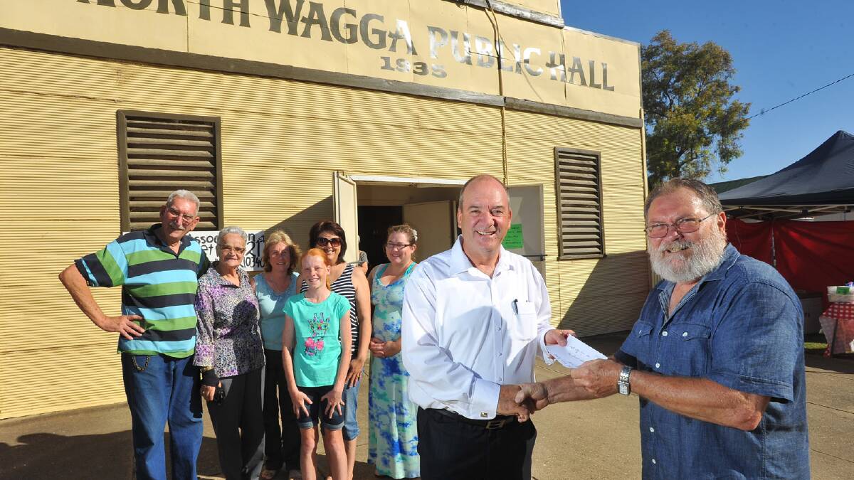 Daryl Maguire handing over a $3000 cheque to the North Wagga Residents Association to re-paint the North Wagga Public Hall. President, North Wagga Residents Association Laurie Blowes received the cheque with community members Dieter Eschbach, Annie Eschbach, Cheryl Conway, Sophie Crouch, Kylie Lonergan-Prowse and Melina Skidmore looking on. Picture: Addison Hamilton