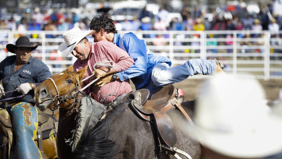 WRESTLING CONTROL: A rodeo competitor clings to Tumbarumba's Dave Daniel for dear life after jumping off his bucking bronc. Pictures: ASH SMITH