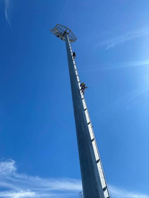 HIGH CLIMB: JRC Electrical Services steadily but surely climb to the top of Robertson Oval's floodlights. Picture: Courtesy of Rob Ellison