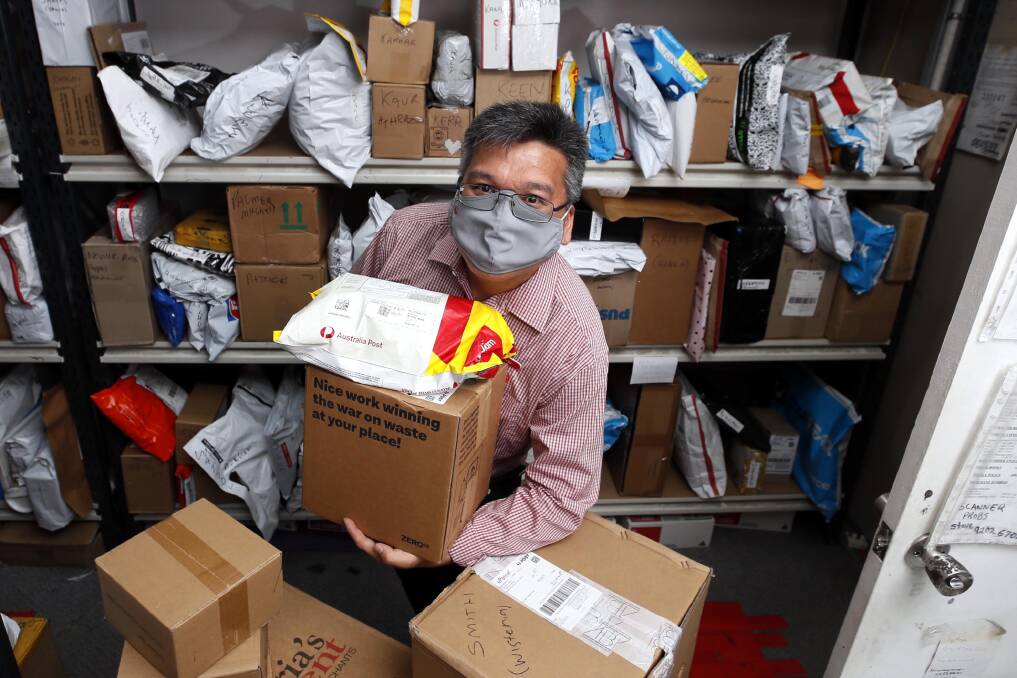 PARCEL PILEUP: Kooringal Post Office licensee Troy Nguyen sorts through a pile of parcels in preparation for delivery. Mr Nguyen has been inundated with an increased number of customers sending parcels. Picture: Les Smith 