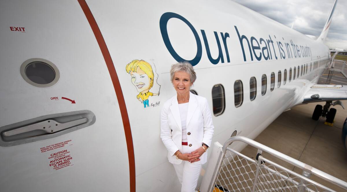 IMMORTALISED: Former Riverina MP and Regional Express ambassador Kay Hull poses next to a caricature honouring the critical role she played during the establishment of the airline. Picture: Supplied.