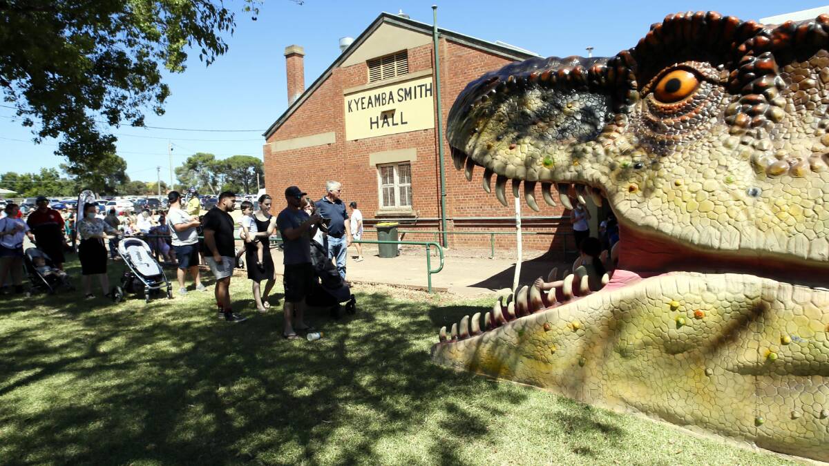 Jurassic queue: Punters wait patiently to get a snap with the giant dinosaur's head. Picture: Les Smith 