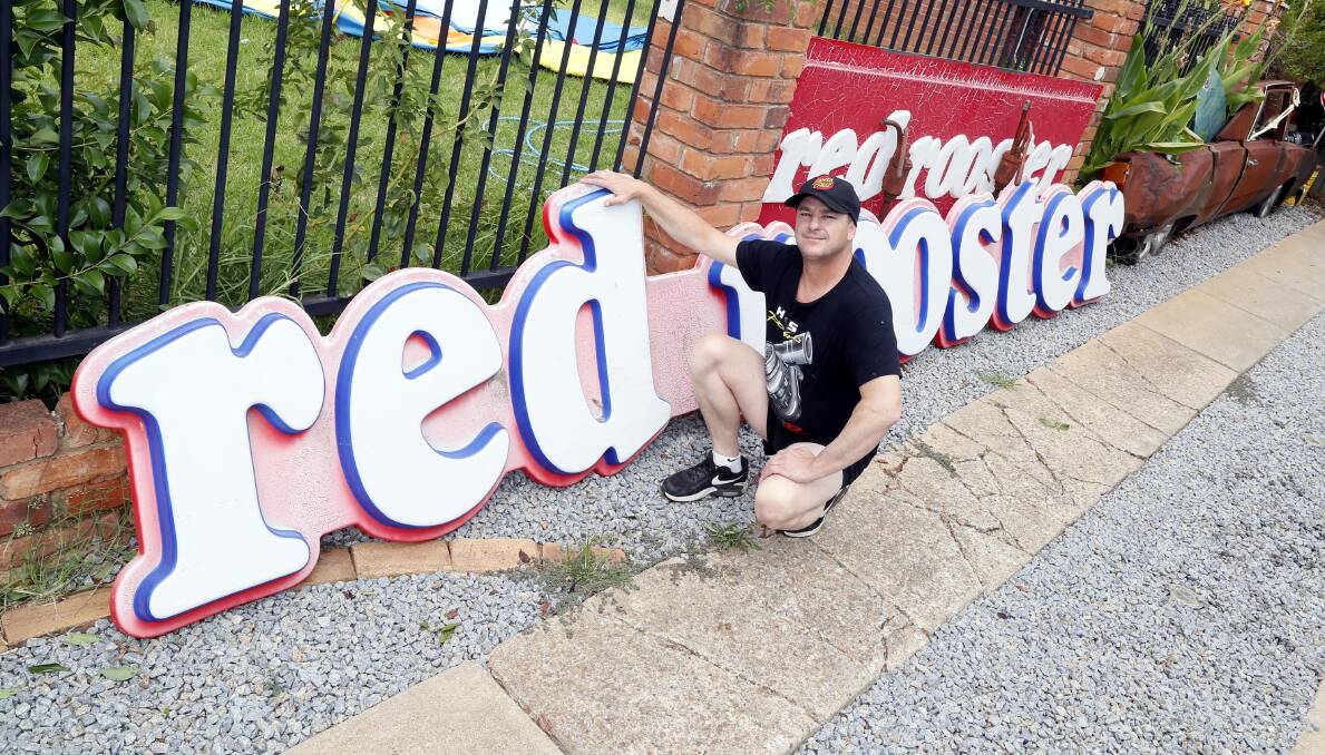Matthew Keppie stands beside some old Red Rooster signs he salvaged from Wagga Tip shop. Picture by Les Smith