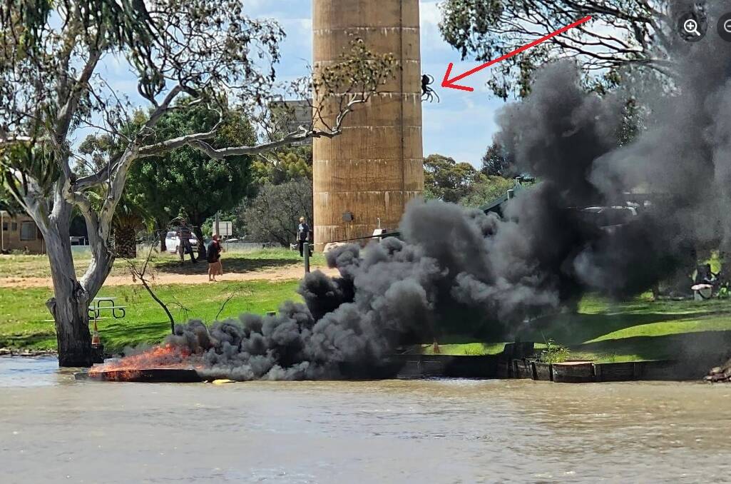 The boat was still smouldering at 3pm on Thursday, December 28. A Federation Council crew removed it from Lake Urana. Andrew Whitehead's spider sculpture is indicated. Picture supplied