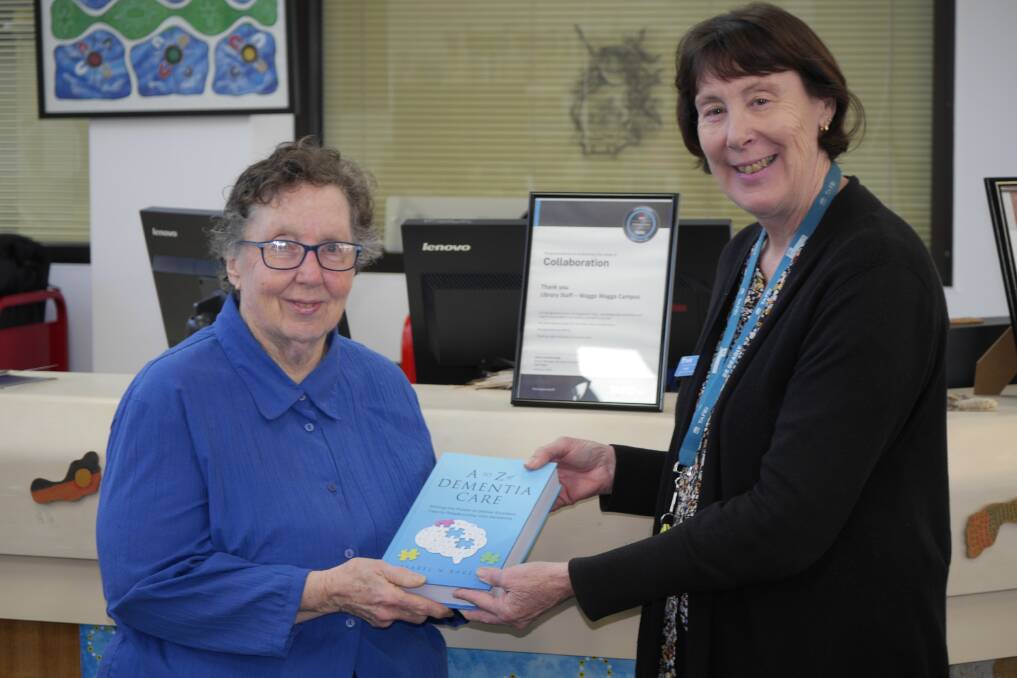 Renowned Wagga dementia expert Isabel Baker hands over her new book, A to Z Dementia Care, to librarian Dianne Klimpsch at the Wagga TAFE on Wednesday. Picture by Andrew Mangelsdorf