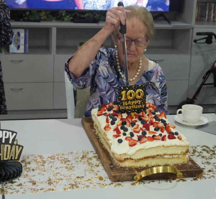 Marie Laughton cuts her cake as she celebrates her 100th birthday in Wagga on Friday. Picture by Andrew Mangelsdorf