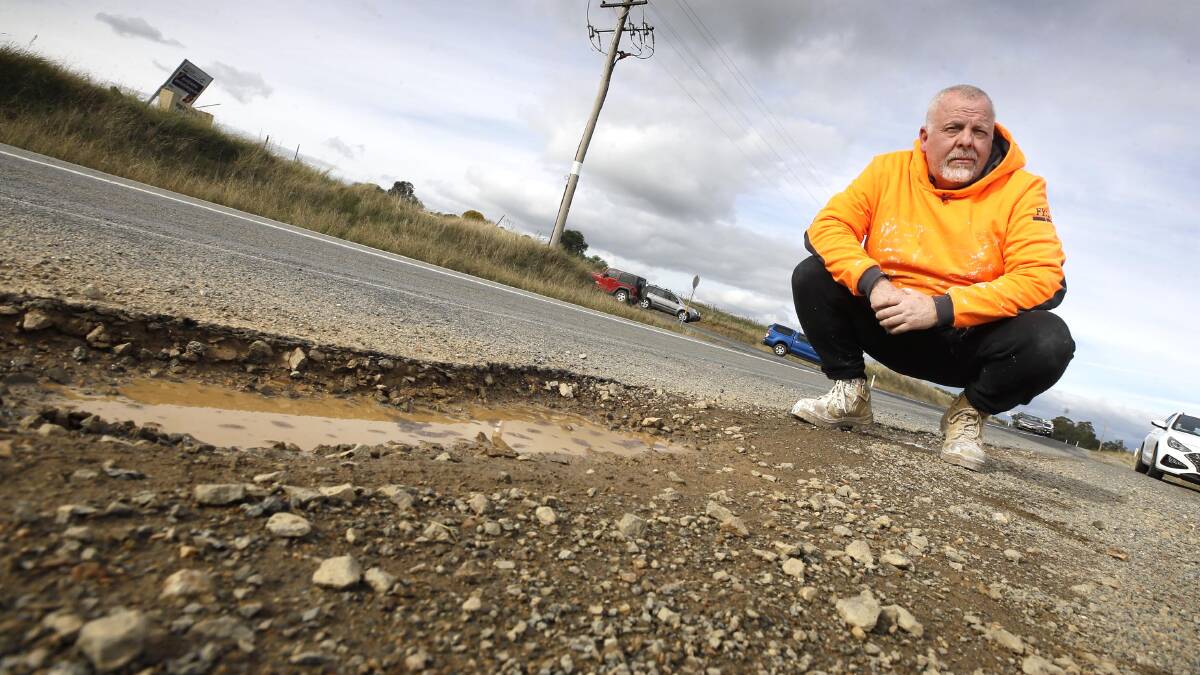 BROKEN ROAD: Councillor Richard Foley beside the crumbling intersection of Pine Gully Road and Old Narrandera Road. Picture: Les Smith