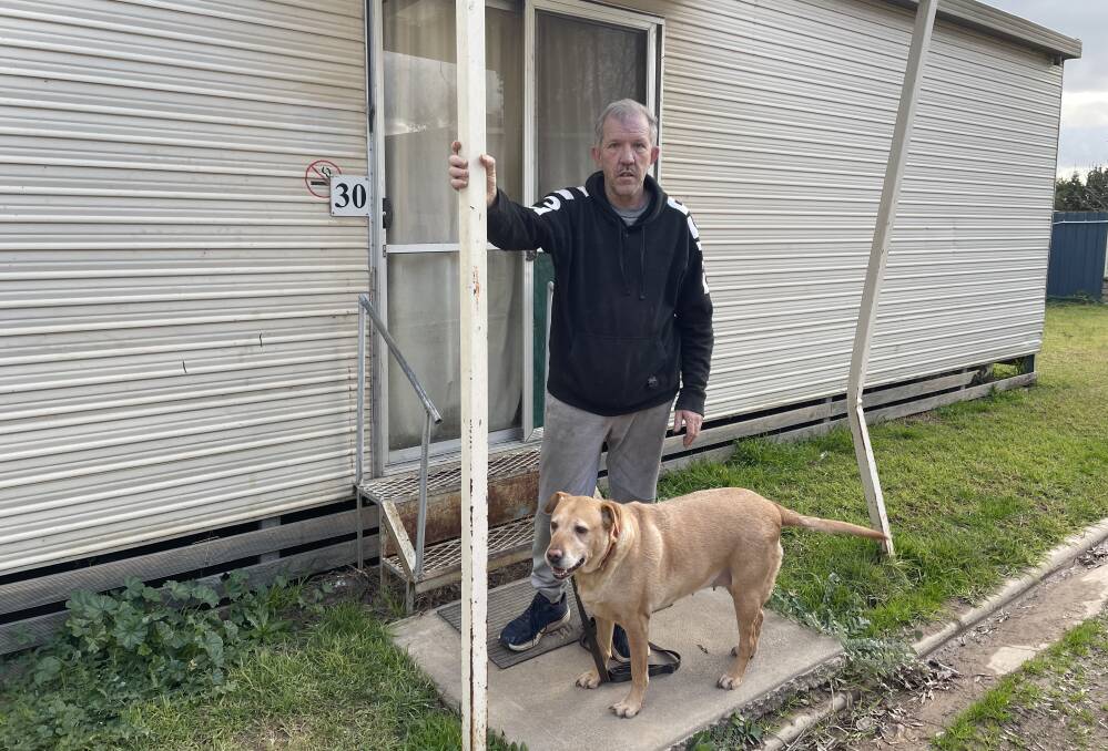 SHORT STRAW: Richard Whitlock with dog Lucy stands beside his cabin at the Tourist Caravan Park. 