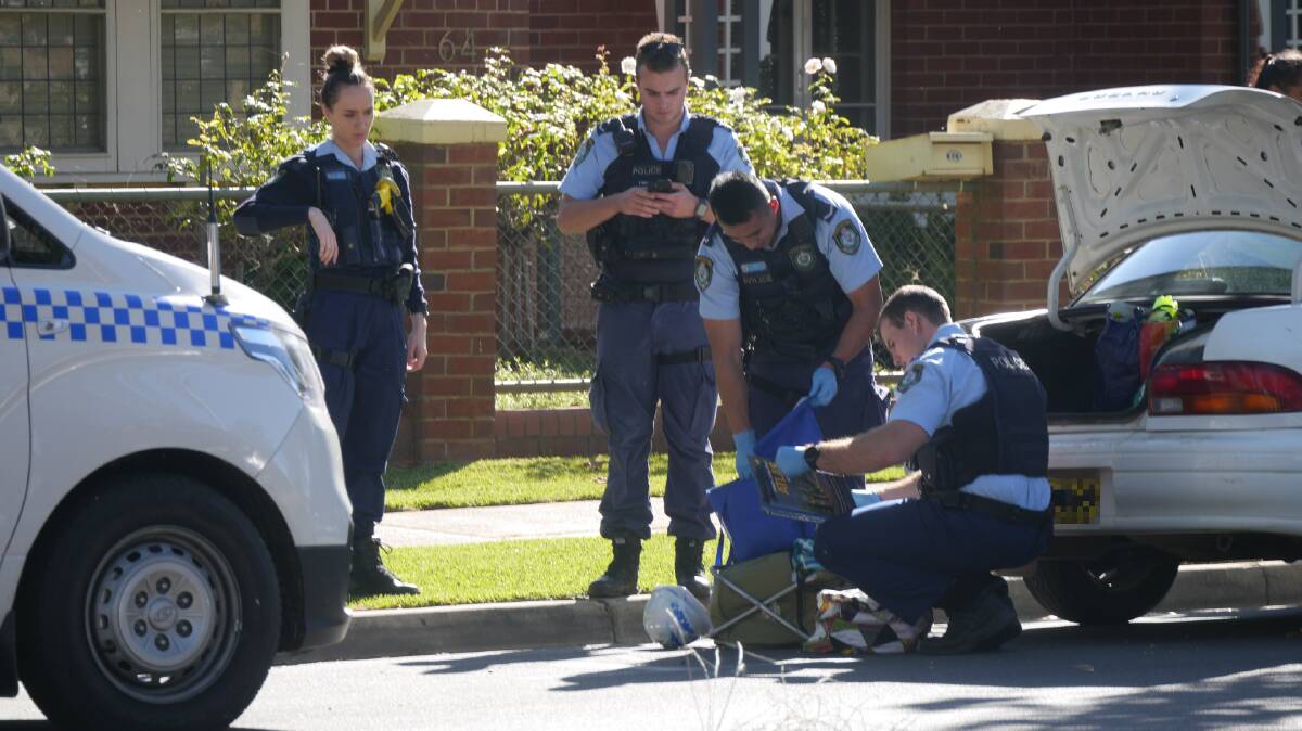 BOOT SEARCH: Police look through the contents of a white sedan at the scene of an arrest on Peter Street this week.