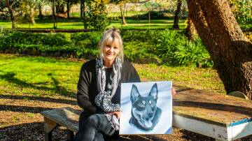 Artist Cathy Hamilton with a canvas print of her graphite drawing of Roy the Kelpie who ate Godfrey the guinea fowl.
