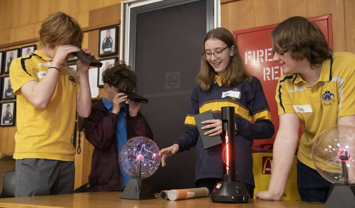 LOOKING AT LIGHT: Brothers Luke, year 9, and Michael Johnson, year 6, (left) use spectrometers to view a neon light while Stephanie Houghton, year 9, and Riley Williams experiment with plasma balls. Picture: Madeline Begley