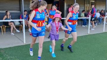 Turvey Park players are led to the ground by one of Wagga's all-girls Auskick players. Picture by Les Smith