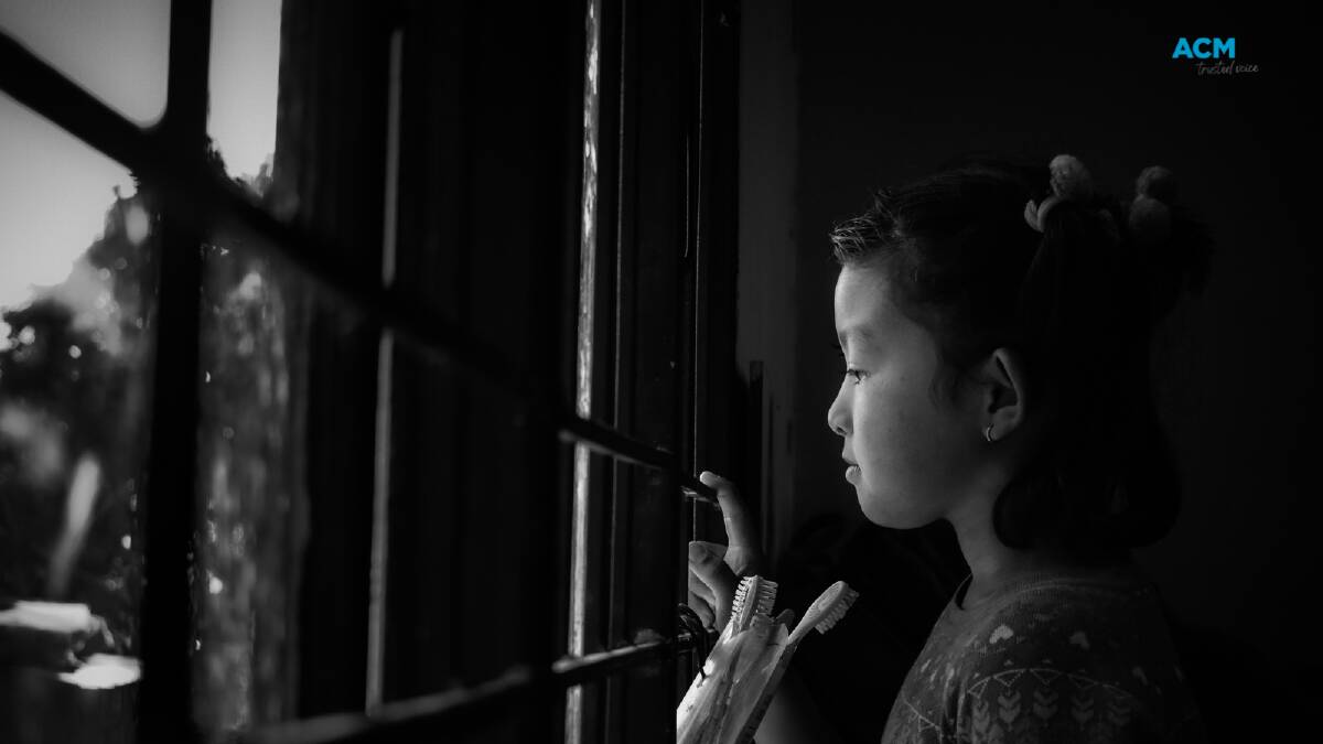 A young girl looks out the window. Picture by Puskar Rai via Canva