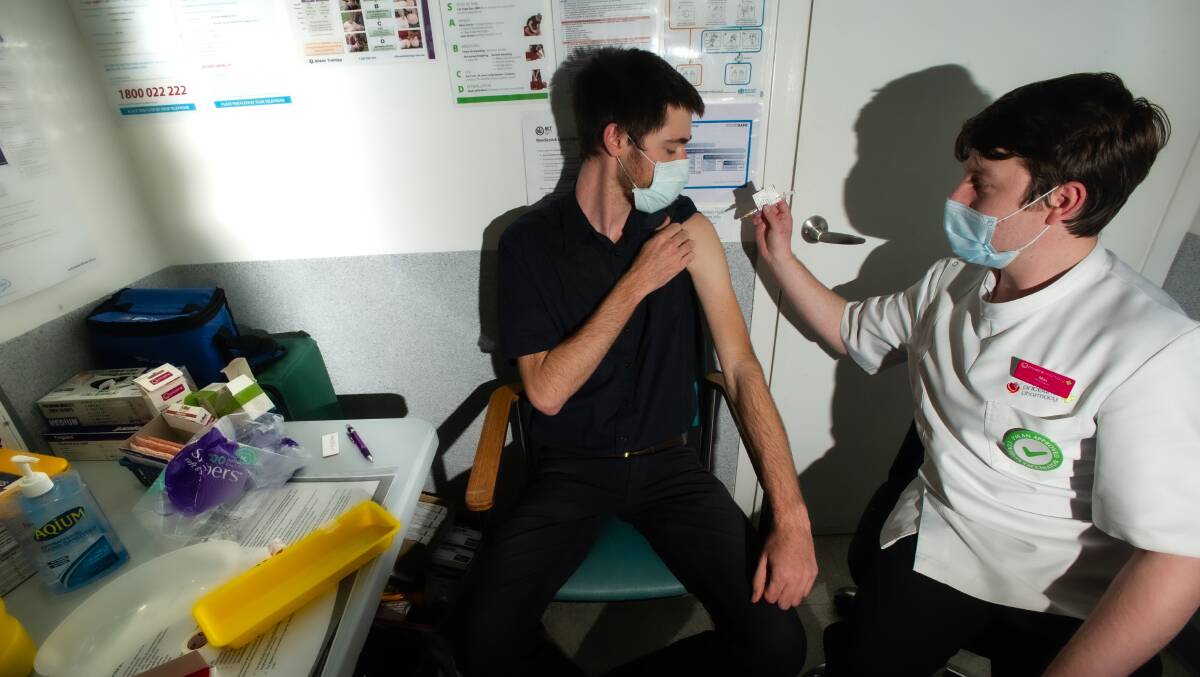 Ash Snare, 26, receives his first dose of AstraZeneca from pharmacist Max Cornwell Laidlaw at Priceline Woden on Tuesday. Picture: Karleen Minney