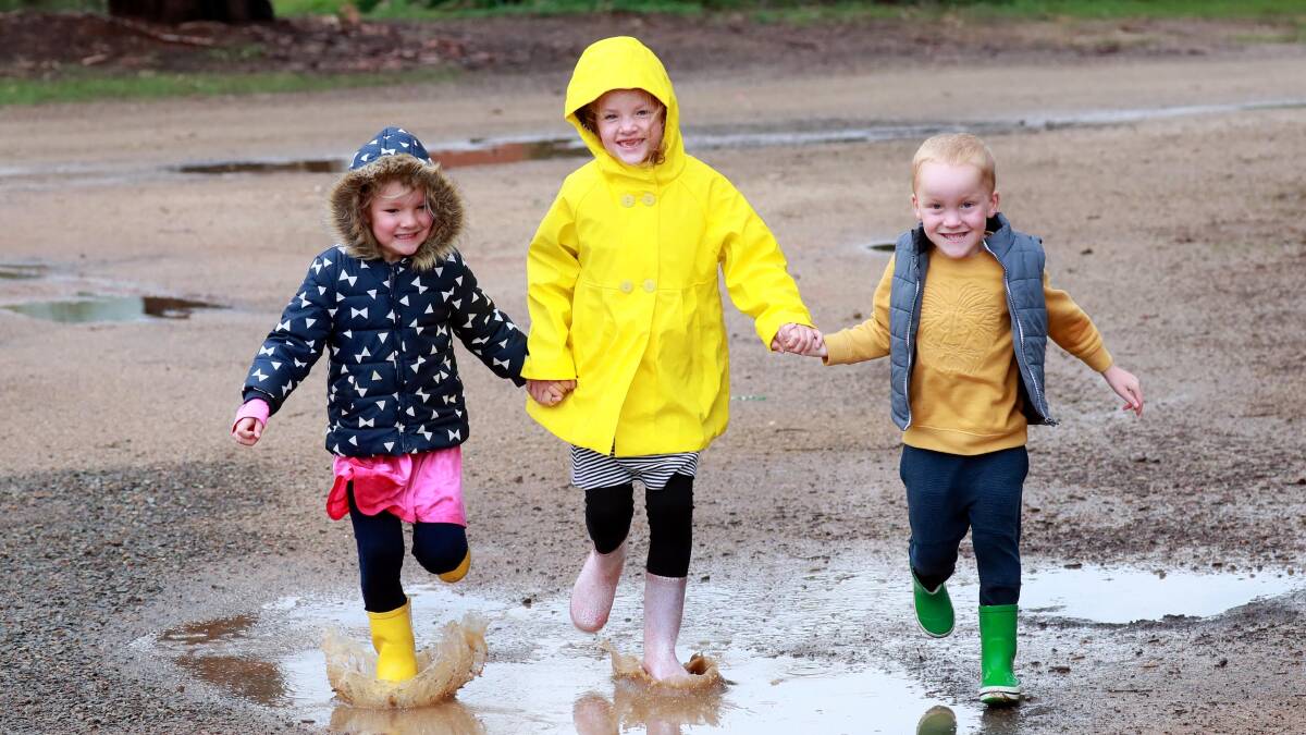 MAKING A SPLASH: Charlotte and Oliver Douglas, 4, with their sister Eliza, 6, jump in puddles near their home at Lake Albert during a bout of wet weather last year. Picture: Les Smith