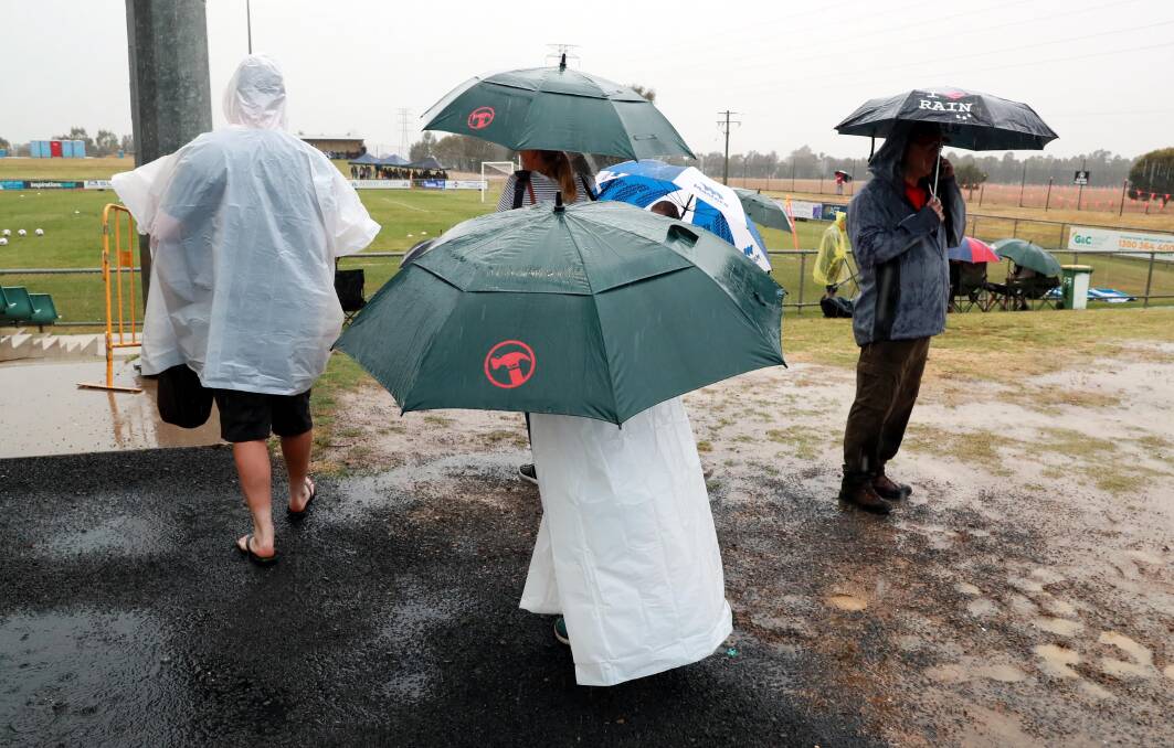 HEAVY RAIN: Spectators look for a dry vantage point during Sunday's W-League trial match at Equex Centre. 