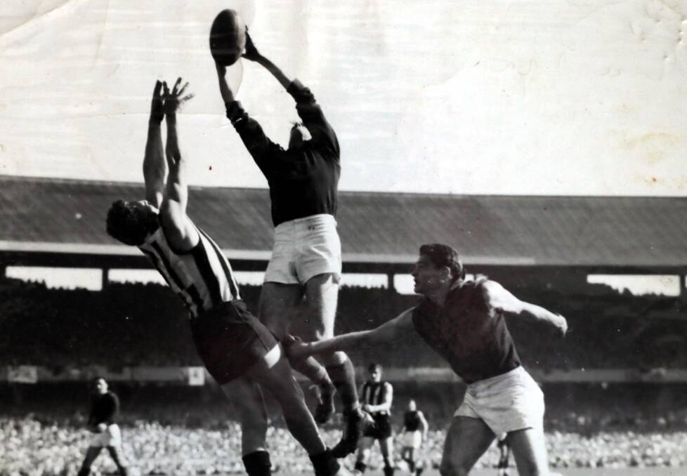UP THERE: Athol Webb soars high to take a mark as high profile teammate Ron Barassi (right) looks on. 