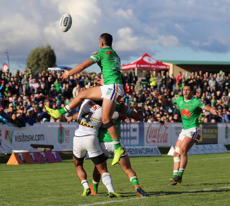 BIG TURNOUT: Raiders winger Bailey Simonsson flies high to take a kick in front of a packed crowd at Wagga early this month. Picture: Les Smith. 