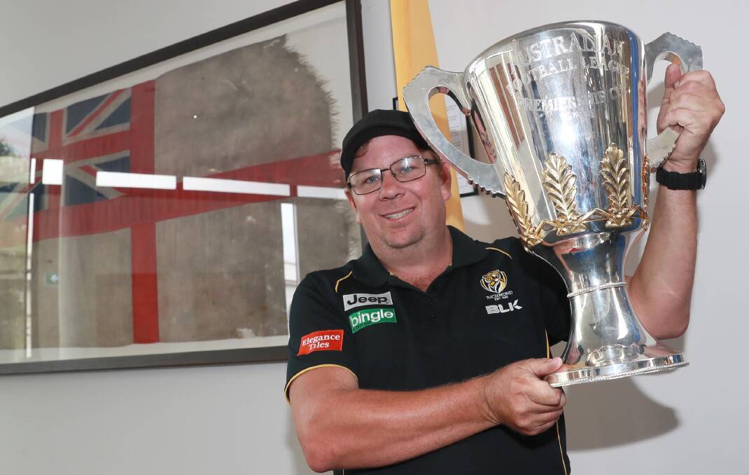 HOLY GRAIL: Wagga-based Richmond fan James Garnsey gets up close with the AFL premiership cup at Wagga Civic Centre on Wednesday. Picture: Les Smith