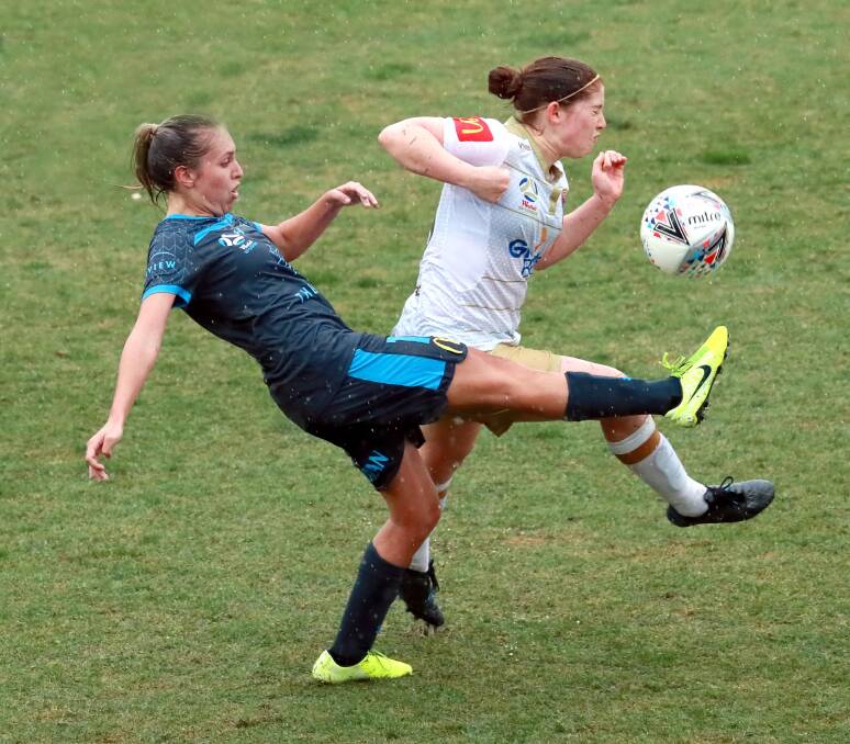 TOUGH CONDITIONS: Sydney FC's Mackenzie Hawkesby and Newcastle's Annabel Martin compete for the ball on Sunday. 
