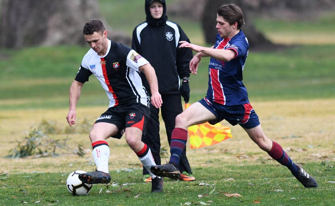 TOUGH CONDITIONS: Leeton's Jarred Flynn and Henwood Park's Ash Woehler battle it out at a wet Rawlings Park on Sunday. 