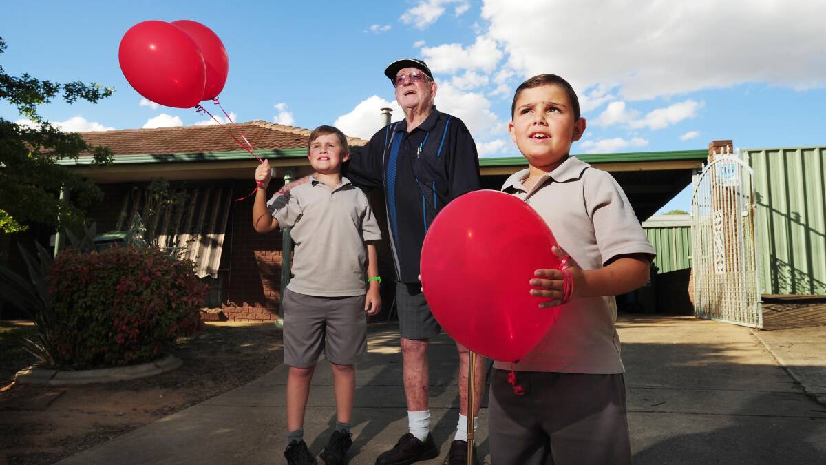 FOR KATHLENE: Bill Stevenson with neighbours Harry Mills, 10, and Fletcher Mills, seven, released balloons for his late wife. Picture: Kieren L Tilly