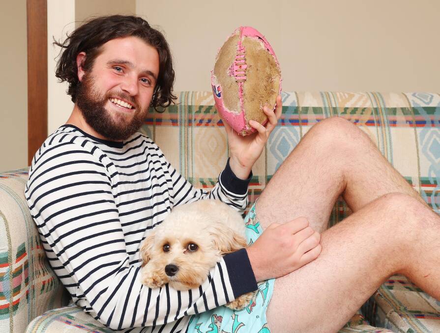 NEW BEGINNING: New Ganmain-Grong Grong-Matong recruit James Wilson at home with dog Archie and his damaged footy on Friday. Picture: Kieren L Tilly