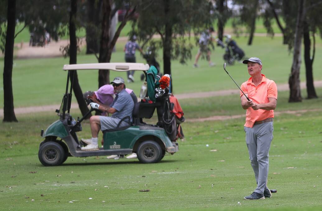 RELAXED: Col Carroll hits his approach to the ninth green during the Wagga Country Club championships last month. The club this week eased restrictions and is now open to members' guests. Picture: Matt Malone